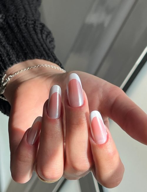 A closeup image of a female hand with professionally painted nails in natural tones