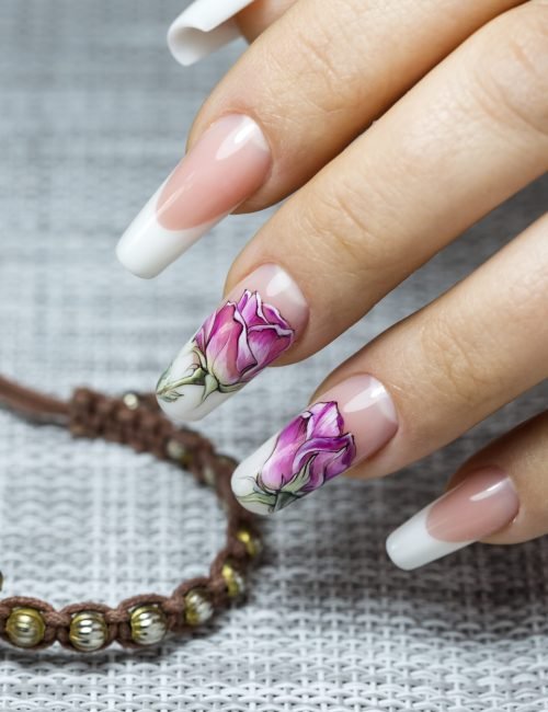 Beautiful multicolored flowers on a transparent lacquer on the nails on a gray decor